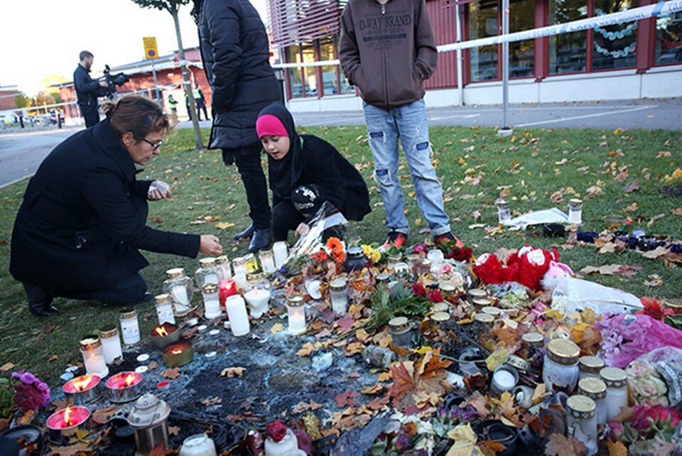 Vuxna och barn samlas utanför Kronans skola i Trollhättan för att hedra offren. Foto: TT-Bild
