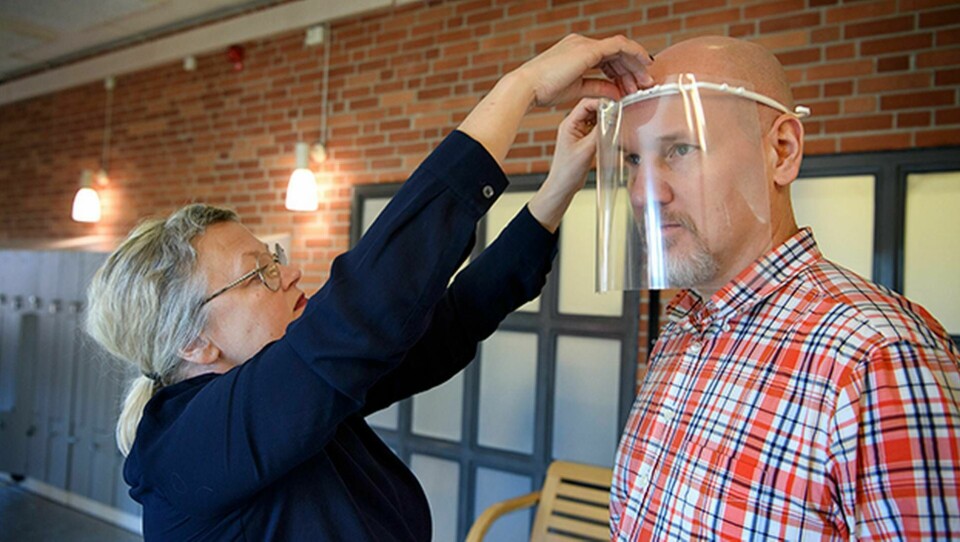 Rektor Monica Nyberg provar ett skyddsvisir på teknikläraren Robert Hegestedt. Foto: Jessica Gow/TT